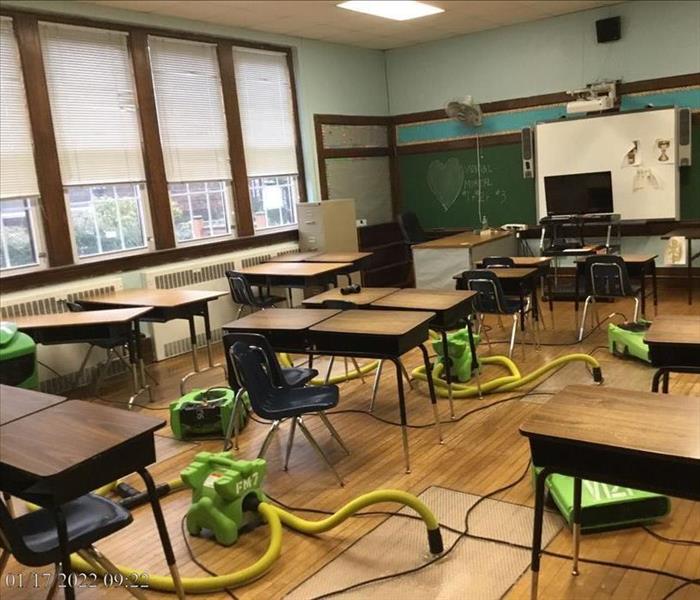 A classroom with hardwood floors and SERVPRO suction pads and air movers operating